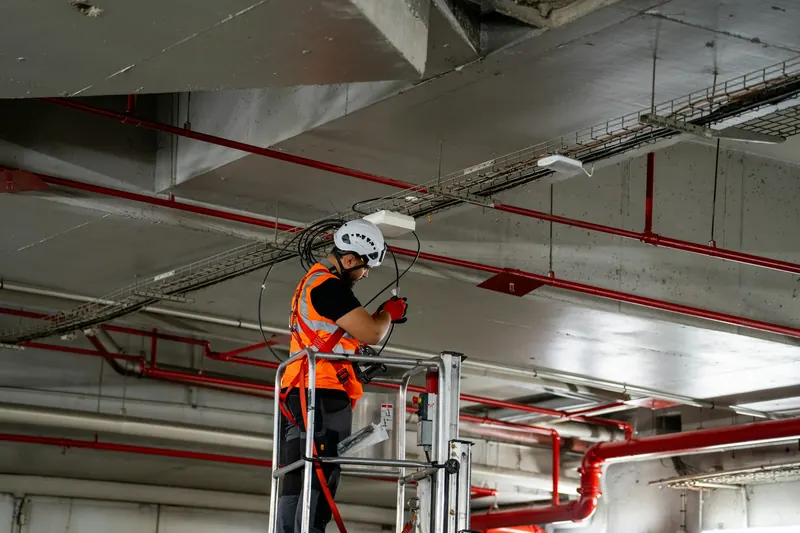 Engineer on a mobile elevating work platform fitting ceiling services