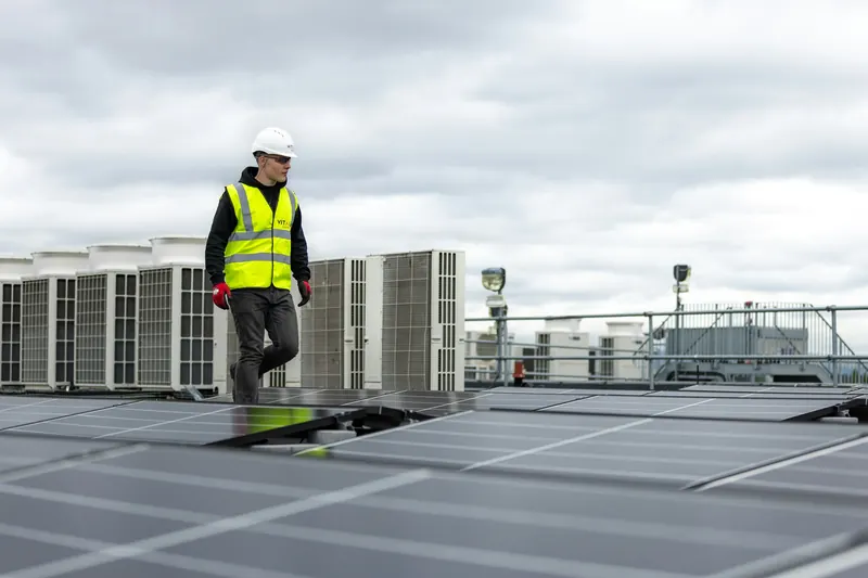 Engineer in hi-vis on a roof beside rows of condenser units